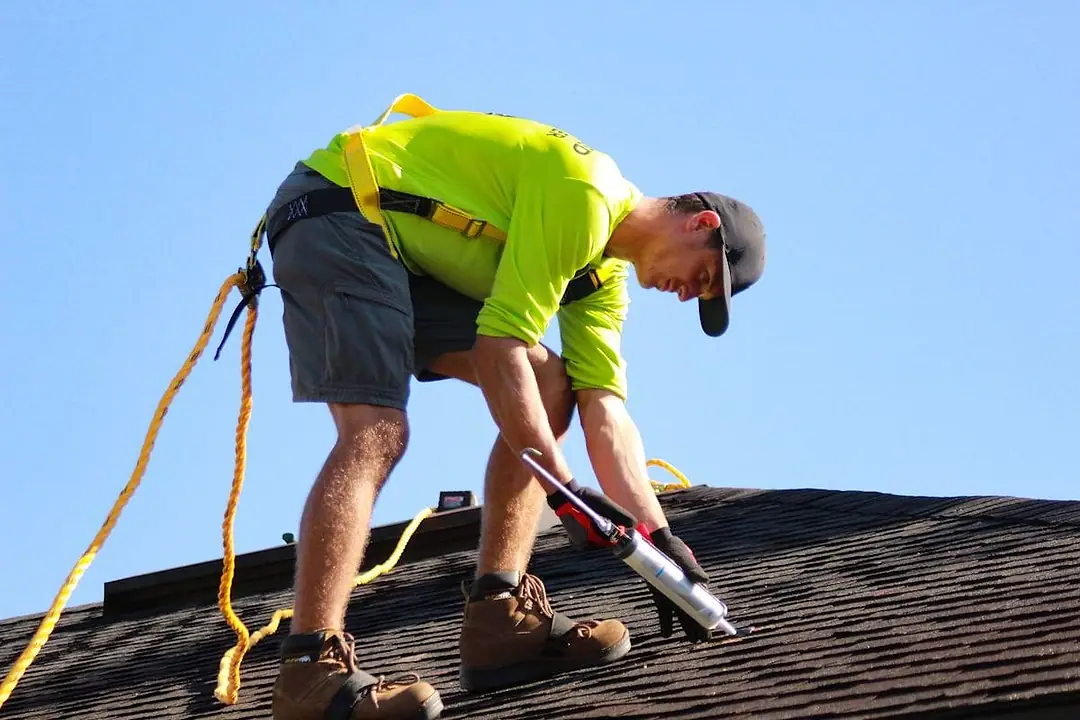 A roofing contractor inspecting an asphalt shingle roof slope.